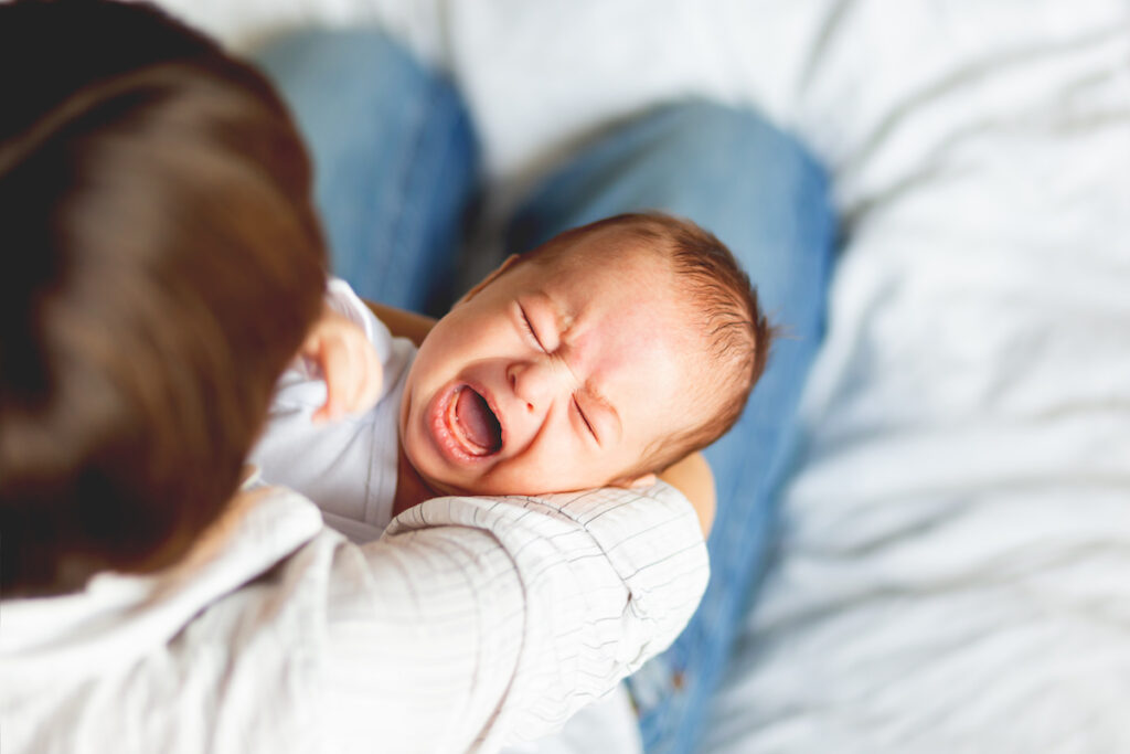 Bedürfnisse von Kindern erkennen, Bild zeigt ein schreiendes Baby im Arm seiner Mutter